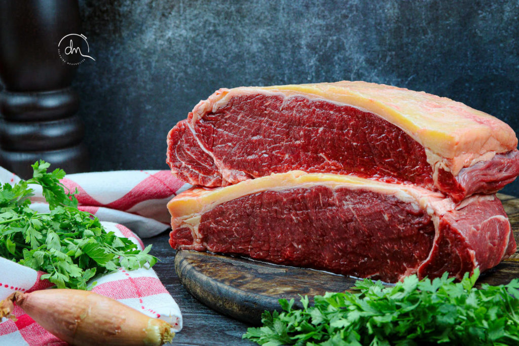 Faux-filet de Blonde de Galice cru, épaisse pièce persillée sur planche en bois