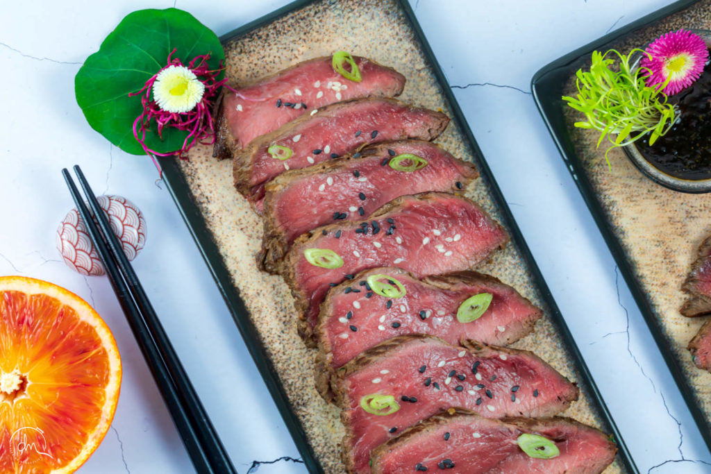 Gros plan sur le Tataki de Cœur de Rumsteck Angus tranché, sésame et fleur comestible