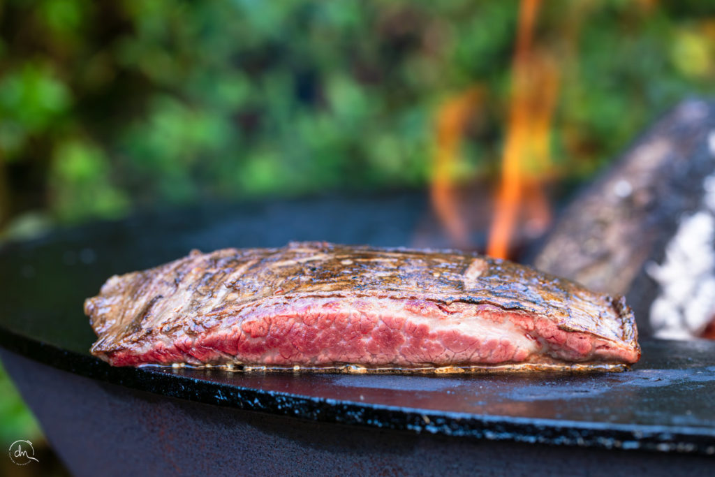 Bavette Wagyu au brasero, croûte caramélisée, gros plan sur les flammes