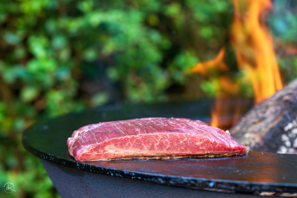 Bavette Wagyu saisie au brasero, flammes en arrière-plan