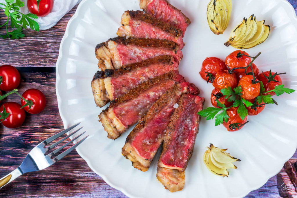 Faux-Filet avec os de Blonde de Galice tranché, avec tomates cerises et oignons grillés