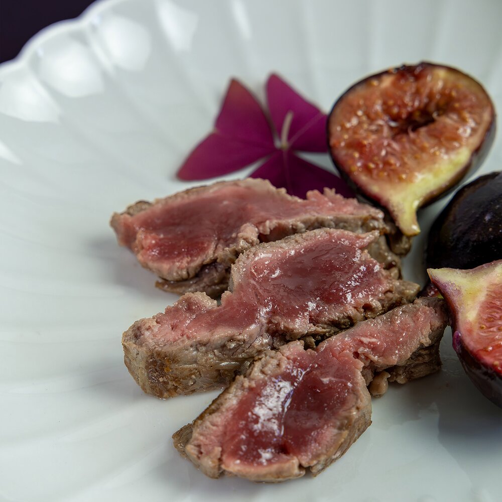 Gros plan sur les tranches d'araignée Fin Gras du Mézenc AOP à côté des figues rôties