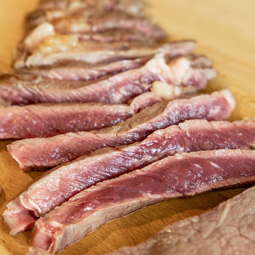 Gros plan sur les tranches d'entrecôte Fin Gras du Mézenc AOP après découpe, cœur rosé et croûte saisie.