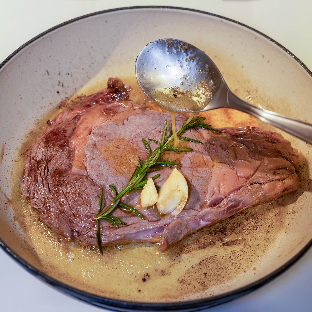 Entrecôte Fin Gras du Mézenc AOP arrosée au beurre parfumé à la cuillère, avec ail et romarin dans la poêle.
